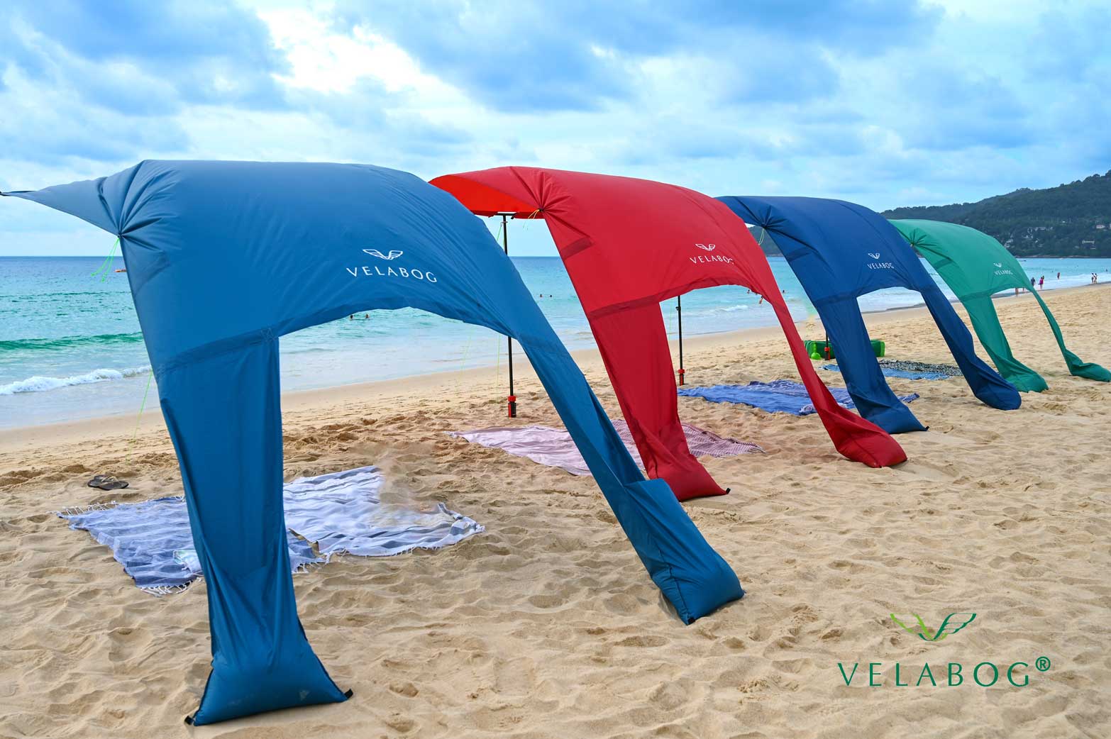 Cztery żagle słoneczne Velabog «Breeze» jako przewiewna ochrona przeciwsłoneczna na plaży. Do użytku przy lekkim lub silnym wietrze. Widok od tyłu.