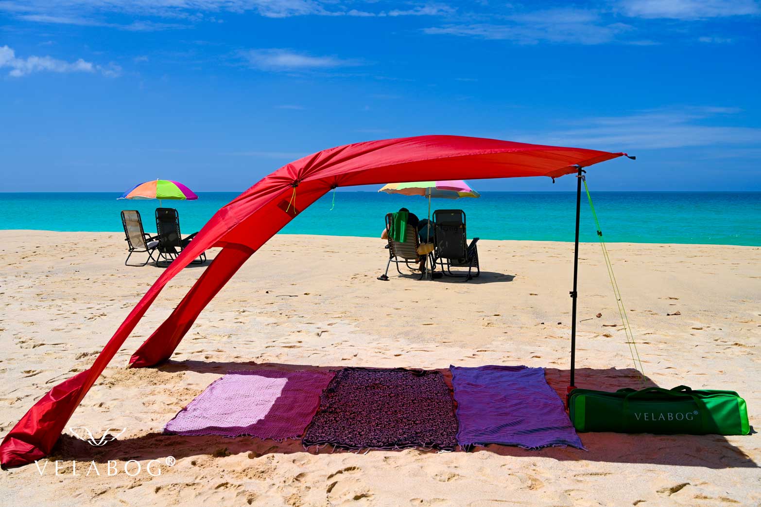 Velabog «Breeze» żagiel słoneczny - czerwony. Najlepsza ochrona przeciwsłoneczna na plaży. Może być używany przy lekkim lub silnym wietrze. Gwarantuje duży cień. Porównanie z parasolami plażowymi.