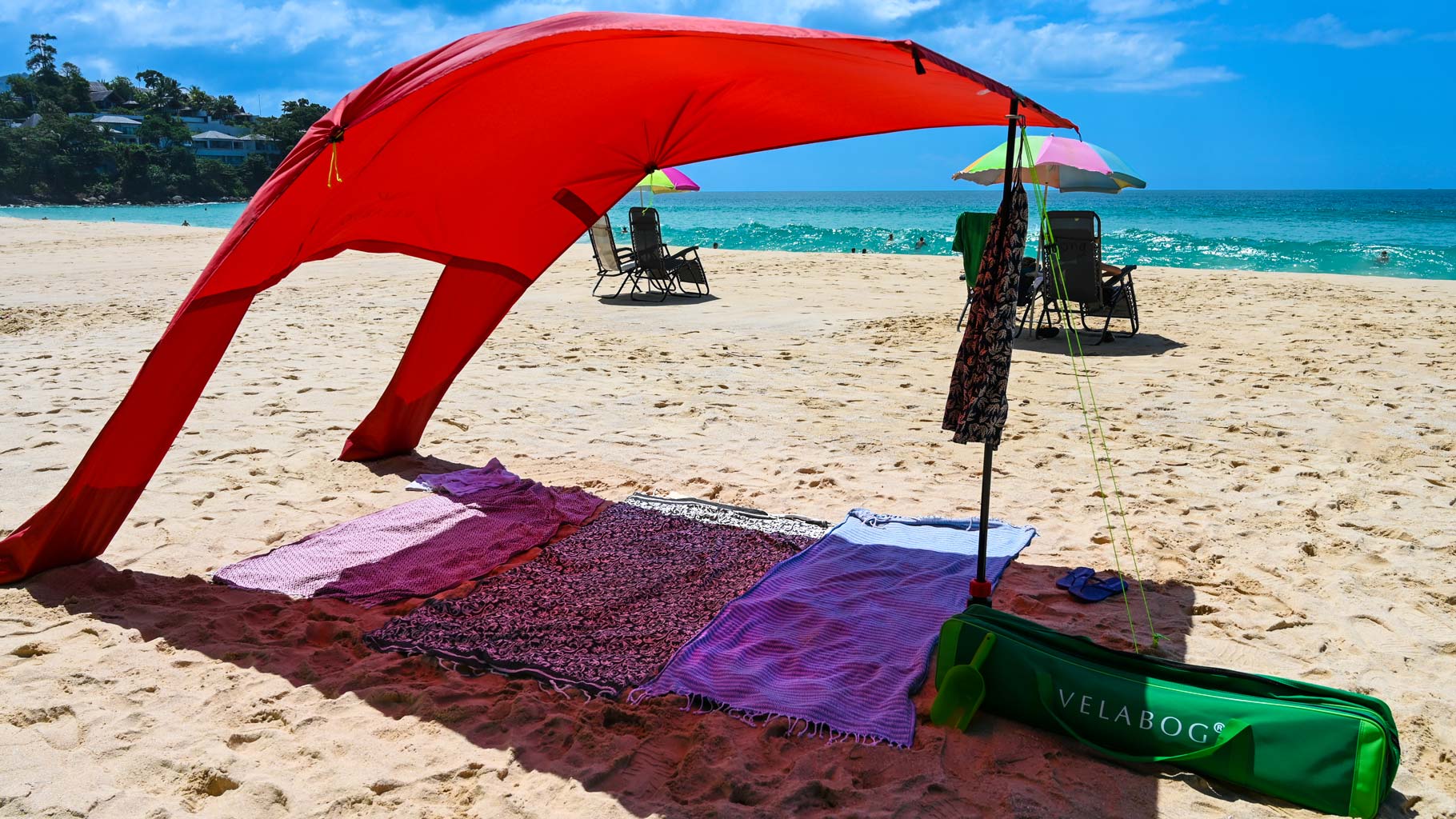 Rotes Strand Sonnensegel Strandzelt Velabog Breeze am Strand mit leichten Wind. Strand Sonnenschirm windfest. Beste Alternative zu Strandschirm, Strandzelt und Strandmuschel. Viel mehr Schatten im Vergleich zu üblichen Strandschirmen.
